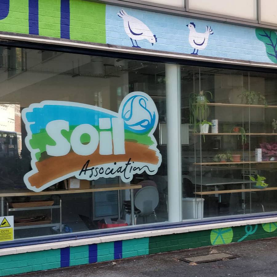 Shop front with Soil Association logo on the window and brightly coloured painted brickwork. 