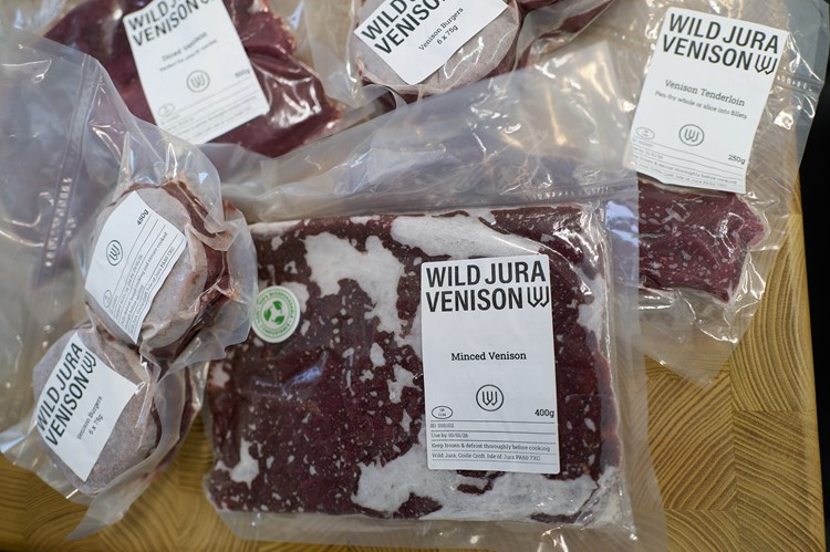 Pile of vacuum packed venison burgers, mince and steaks with Wild Jura logo. 